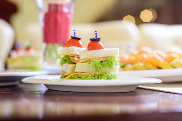 Sandwich with tomato, lettuce, cheese and meat on the white plate