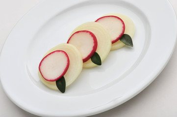 Sliced radishes, onions with bay leaves on a plate