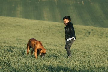 Little boy and dog in field. Boxer dog