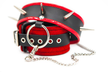 Leather handcuffs and collar with spikes connected by a chain isolated on white background. Sex toy...