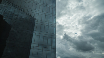 Obraz premium Modern skyscraper with glassy facade and overcast sky. Office building exterior