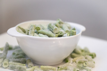Frozen green beans on a white plate. Healthy nutrition. Green vegetables. Preparation for cooking.