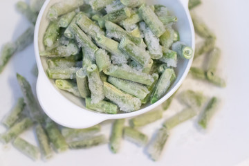 Frozen green beans on a white plate. Healthy nutrition. Green vegetables. Preparation for cooking.