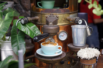 Hot Latte - A cup of coffee with milk and beautiful leaf pattern latte art on wooden table and blurred background, Perfect for breakfast time.