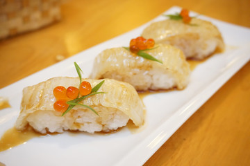 Aburi engawa sushi - Grilled flatfish (Fluke fin) on rice topping with salmon roe (Ikura) served with wasabi and pickled ginger, Japanese traditional food.