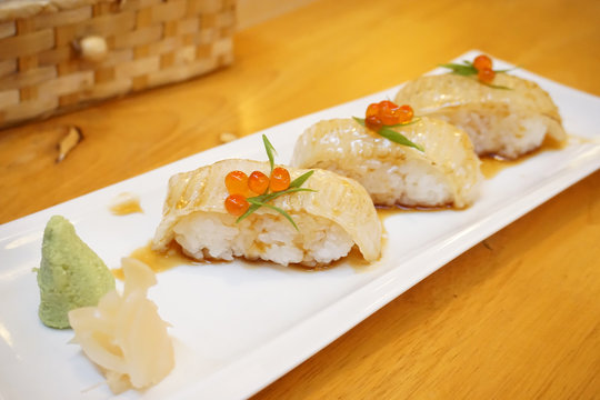 Aburi engawa sushi - Grilled flatfish (Fluke fin) on rice topping with salmon roe (Ikura) served with wasabi and pickled ginger, Japanese traditional food.