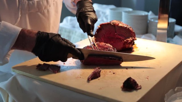 Carving delicious steak on carving station slow motion