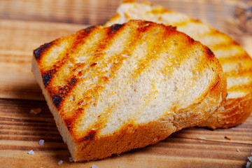 Grilled bread on burned wooden table. Preparing for traditional rural dinner