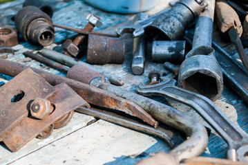 The old tool lies on the table, hammer, wrench, bolts, metal.