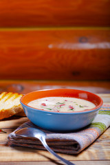 Spicy soup with sour cream, bread and spices on burned wooden table. Traditional rural dinner