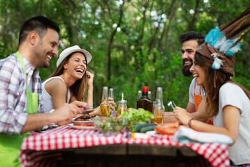 Friends having a barbecue party in nature while having fun