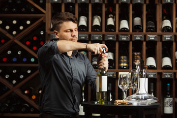 Sommelier opening white wine bottle with corckcrew
