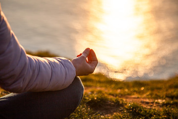 beautiful woman doing yoga by the sea at sunset - yoga, mindfulness, mental health background