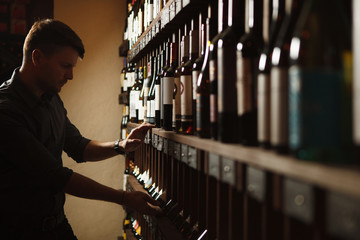 Sommelier taking one of bottles from wooden cellar