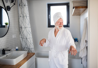 Senior man doing morning routine in bathroom indoors at home.