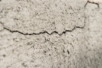 Old foundation and plaster wall with cracks. Building requiring repair closeup.