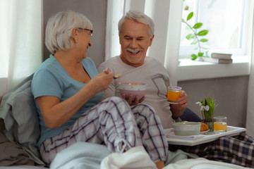 Obraz na płótnie Canvas Joyful spouses sharing a laugh and enjoying breakfast