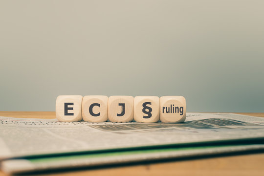 Symbol for a decision of the European Court of Justice (ECJ). "ECJ ruling" written on cubes placed on a newspaper.