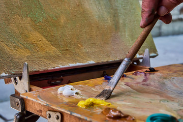 creative image, artist's palette with oil paints and brushes, close-up, old wooden palette, paints of different colors, close-up of the artist's brush