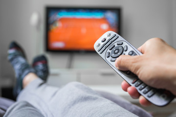 closeup of man relaxed in sofa using tv remote