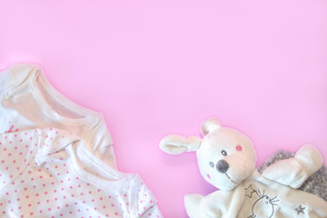 Beautiful set baby accessories - newborn baby clothes and funny toys on pink background. Copy space, flat lay, top view.