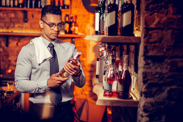 Rich businessman owning bar looking at bottles of alcohol