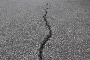 There is a long crack in the tar road.