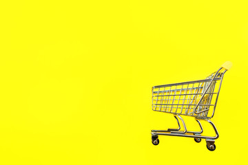 Toy cart for products on a yellow background. Place for text. View from above. The concept of shopping and consumption