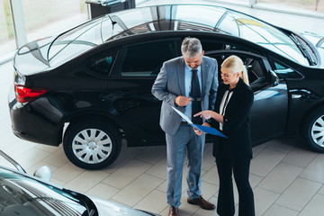 sales agent talking with customer in car dealership showroom