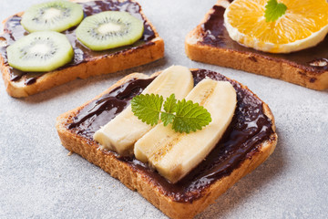 Sandwiches with chocolate paste and various fruits on a gray table. Top view. Concept delicious Breakfast.