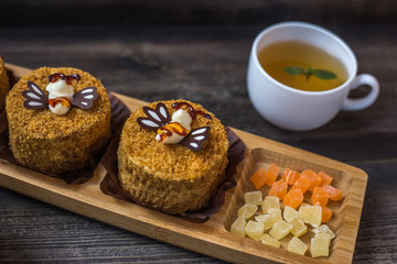 Small layered honey cake with cup of tea on wooden table