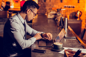 Freelancer checking time while waiting for friend in the bar