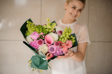 Young blond girl holding bouquet with various flowers