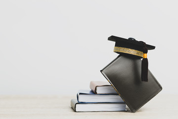 Graduation celebrating cap on stack books on white backgroud, Education knowledge learning study...