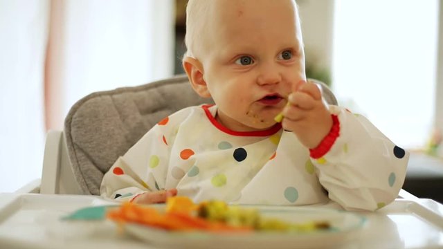 Baby boy eating with BLW method, baby led weaning