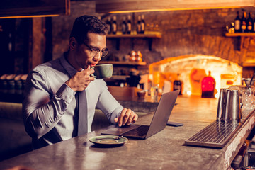Businessman drinking some coffee while working on laptop