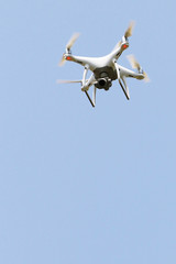 Drone quad copter flying in the blue sky for recording video or take a photo top view. Drone isolated in blue background with copy space.