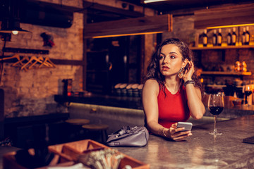 Stylish woman sitting at the bar counter and drinking wine