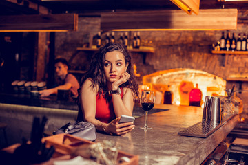Beautiful woman feeling sad while waiting for friend in bar