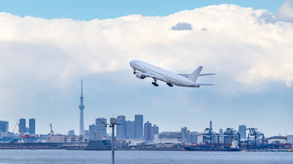 Fototapeta na wymiar 高層ビル群を背景に羽田空港を離陸する飛行機