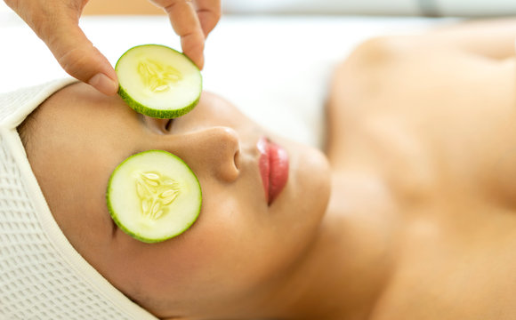 Home spa. Asian girl holding pieces of cucumber on their faces lying the bed and relaxing during spa procedures on face with cucumber. spa environment, Leisure. lifestyle beauty woman concept