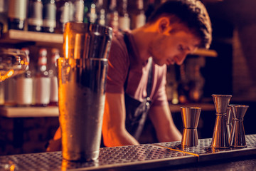 Young barman standing at the bar counter feeling busy