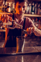 Barman pouring vodka into shaker before making cocktail