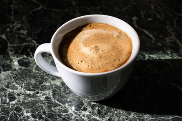 white cup of  coffee on green marble background.