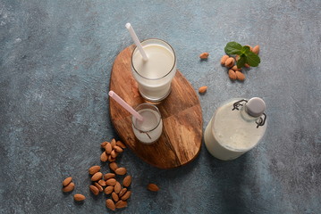 Almond milk in glass bottles with almonds on background. Vegan diary concept. Healthy food and drinks
