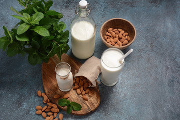 Almond milk in glass bottles with almonds on background. Vegan diary concept. Healthy food and drinks