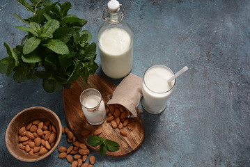 Almond milk in glass bottles with almonds on background. Vegan diary concept. Healthy food and drinks