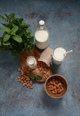 Almond milk in glass bottles with almonds on background. Vegan diary concept. Healthy food and drinks
