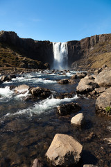 Clean water of famous Iceland waterfalls on a stony rocky mountain landscape