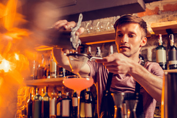 Barman feeling busy while pouring juice through sieve into glass